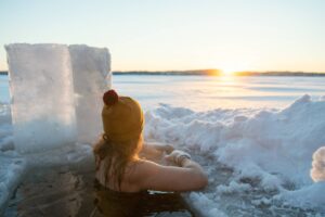 Woman taking an ice bath at sunset on Lake Saimaa, Finland.