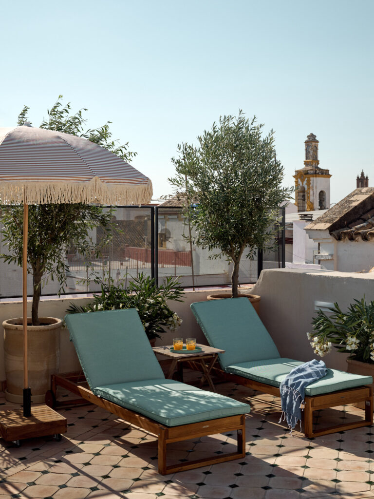 Sun loungers on the rooftop solarium at Casa Cristine Bedfor Sevilla surrounded by greenery and city views.