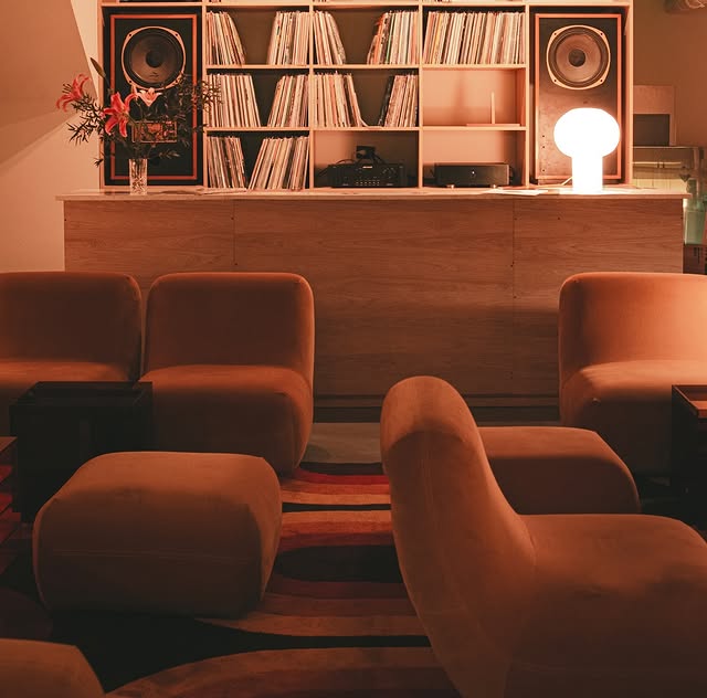 Warmly lit listening room with vintage chairs and vinyl collection at Bimbinilo in Buenos Aires