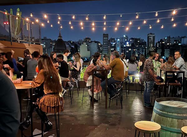 Rooftop bar in Recoleta with nighttime city views, string lights, and people enjoying cocktails on a lively terrace.